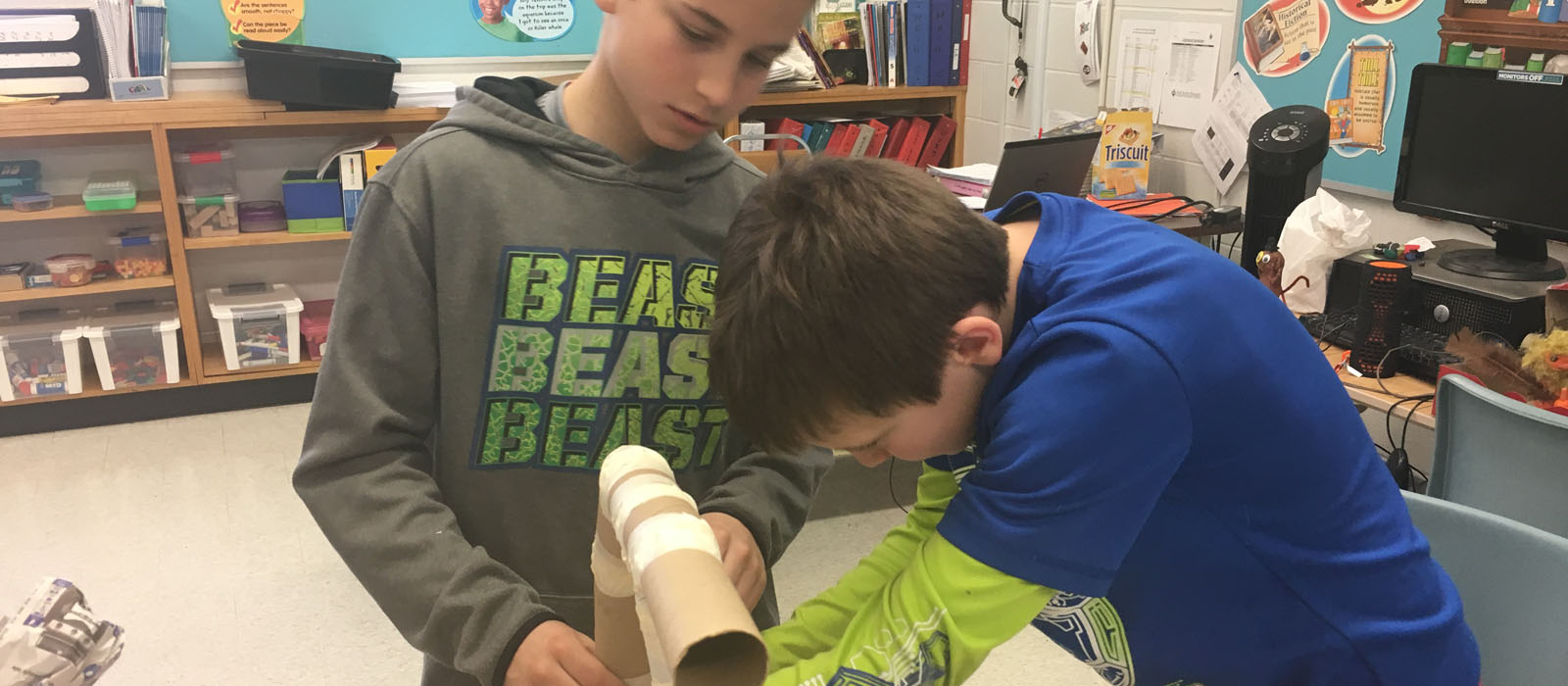 Two male students making something with cardboard